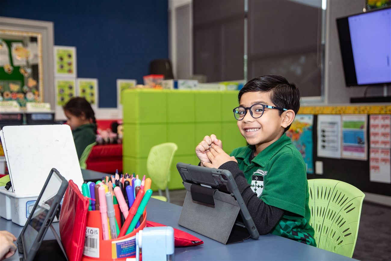 A smiling St Patrick's student at his desk with a tablet
