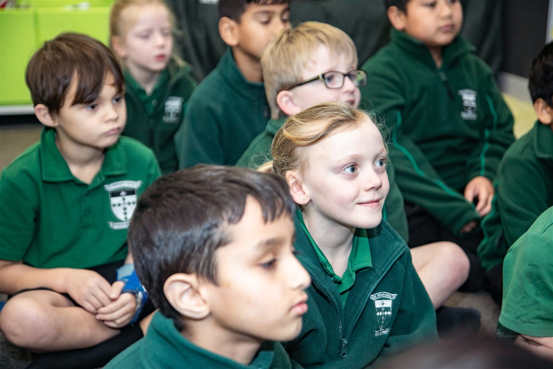 A group of St Patrick's students sitting together on the classroom floor, listening attentively