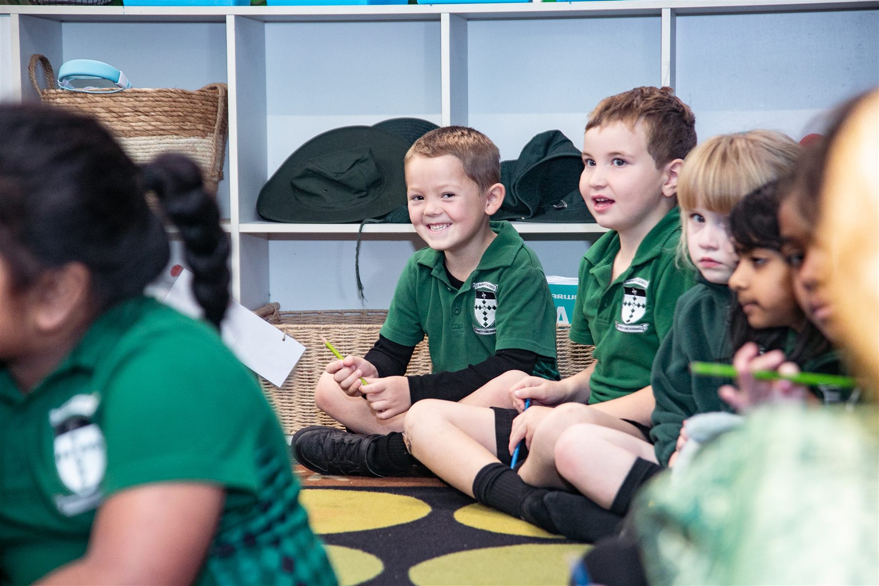 A group of boys sitting cross-legged on the classroom carpet, smiling