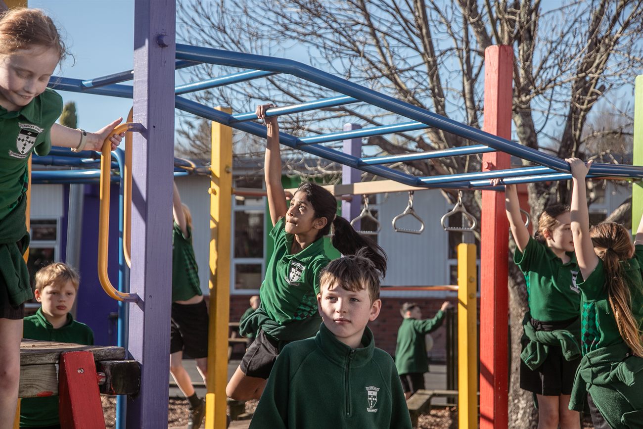St Patrick's students playing together on the colourful playground monkey bars