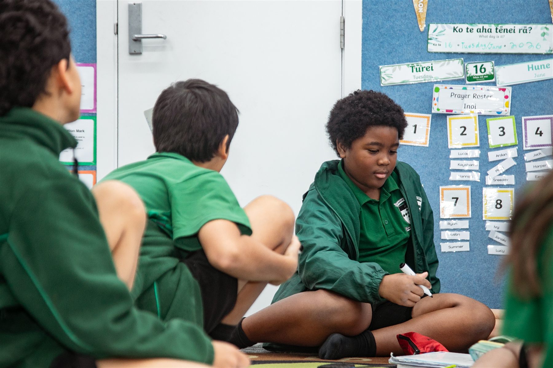 A St Patrick's student working in class beside a noticeboard with the day's date in te reo Māori