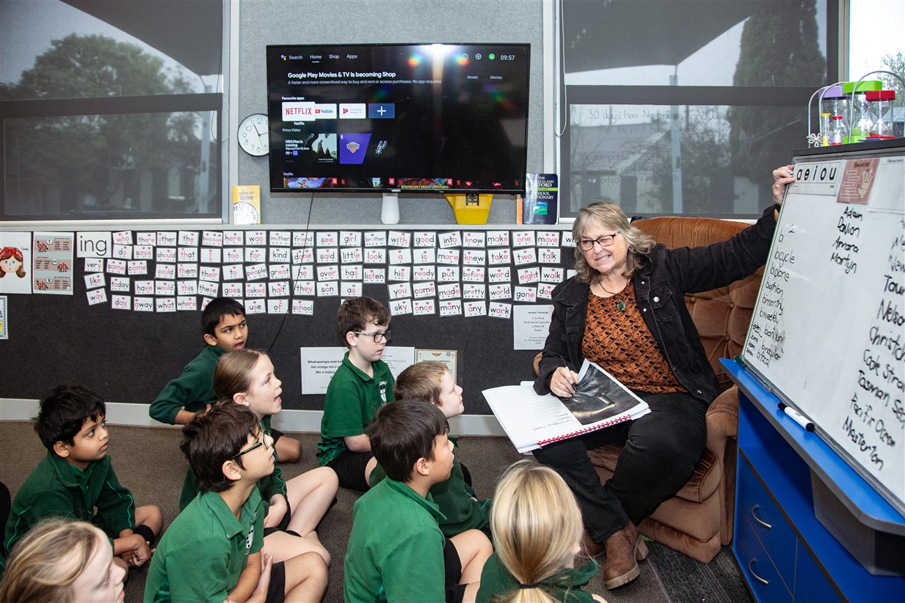 A kaiako reading with a mixed group of St Patrick's students gathered on the classroom floor
