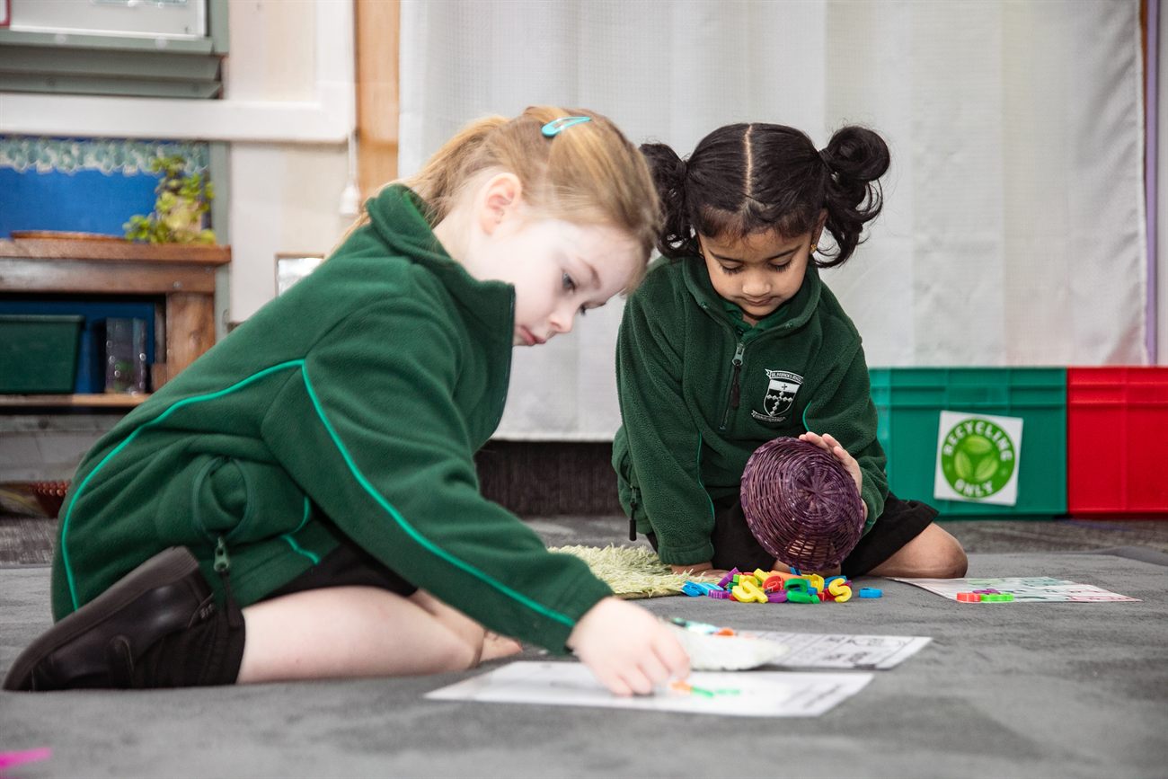 Two young St Patrick's students drawing together on the classroom floor