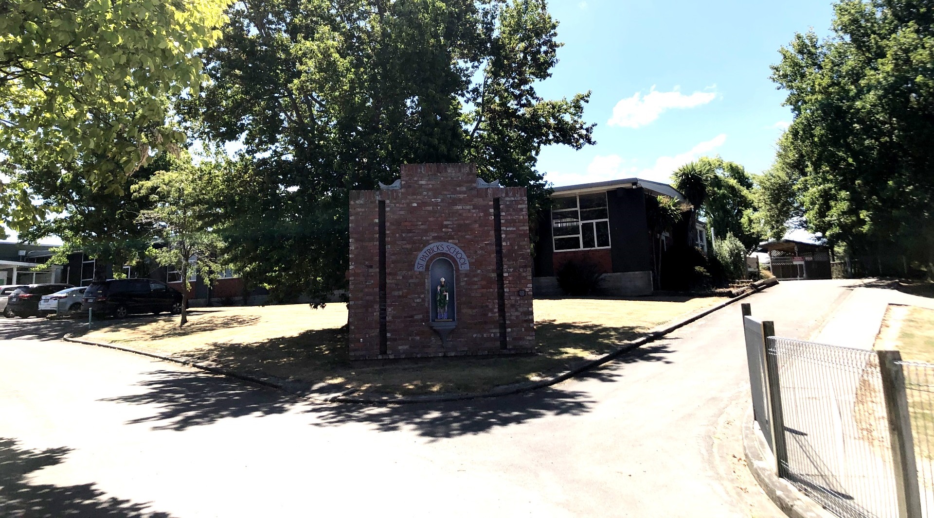 The historic brick wall from the original school building, with a statue of St Patrick set in an arch beneath the words St Patricks School, at the entrance to the school grounds
