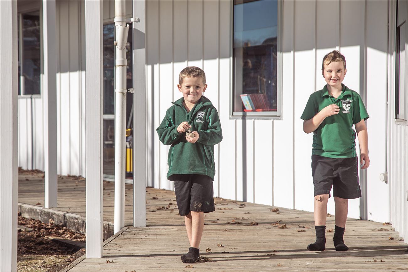 Two St Patrick's boys smiling as they walk along the wooden deck outside their classroom