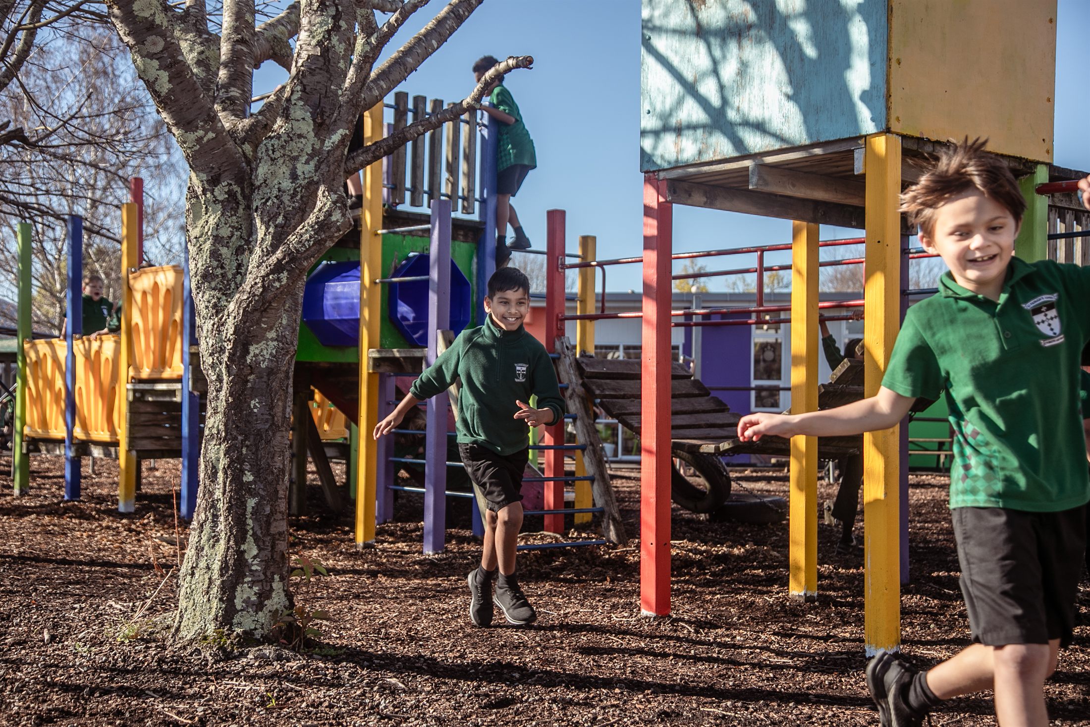 A St Patrick's student grinning as he runs through the colourful school playground with friends