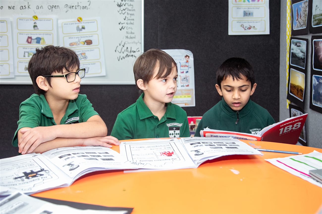 Three St Patrick's boys reading together at a table in their classroom