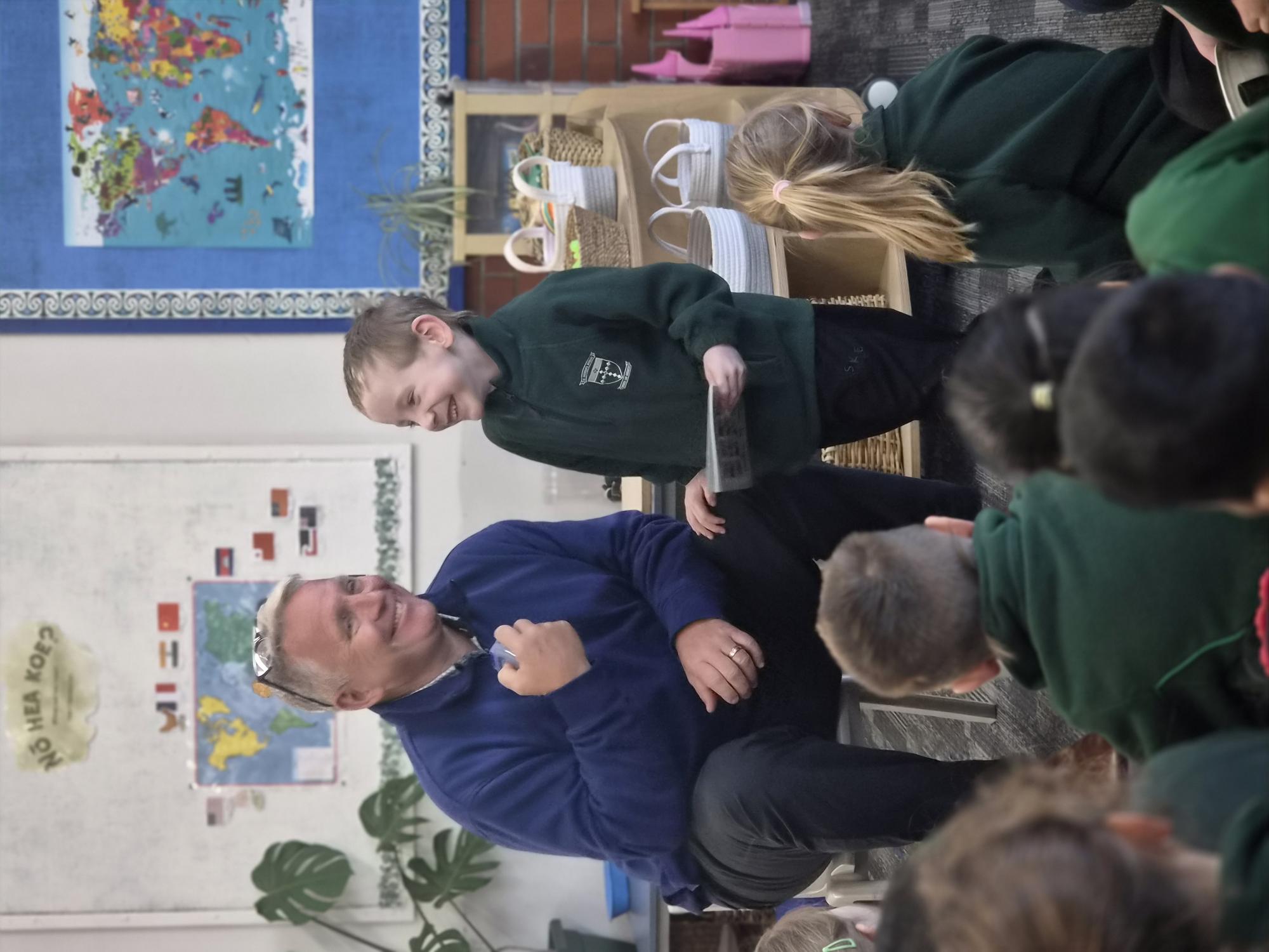 Principal Steve Wheeler sharing a laugh with a young student in front of the class at mat time