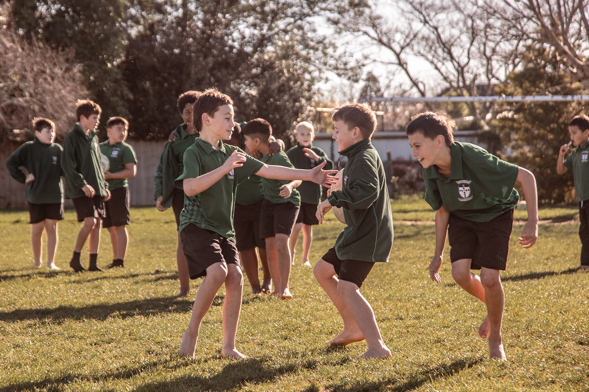 St Patrick's students playing a chasing game together on the school field in the afternoon sun