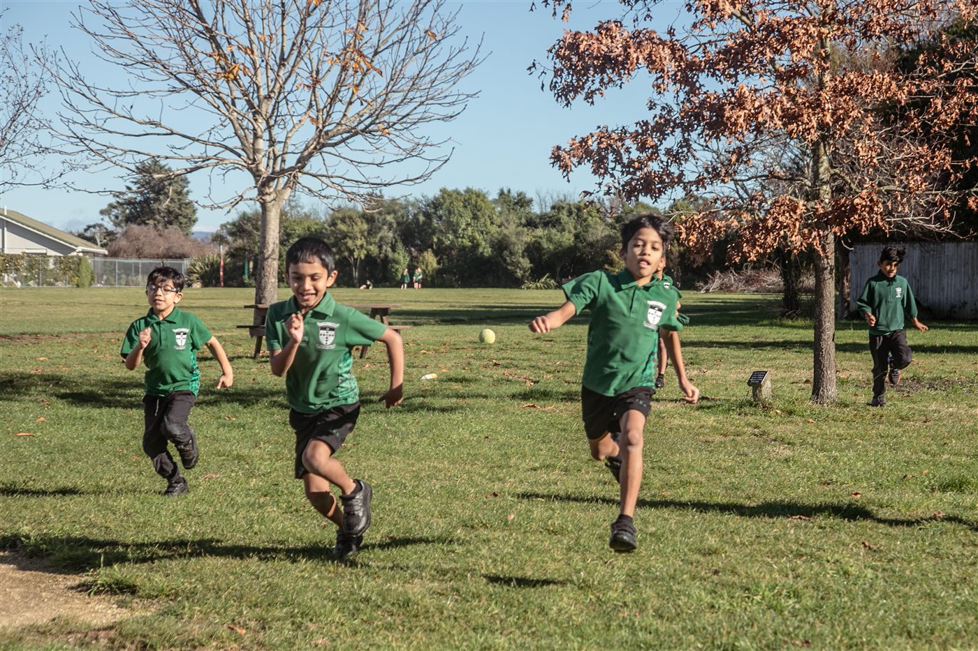 Three St Patrick's boys running across the school field in the afternoon sun